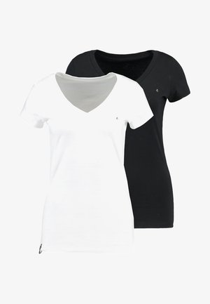 Dva prilagođena V-izreza majice: jedna bijela, druga crna. Obje imaju kratke rukave, mekani materijal i mali logo na lijevoj strani.