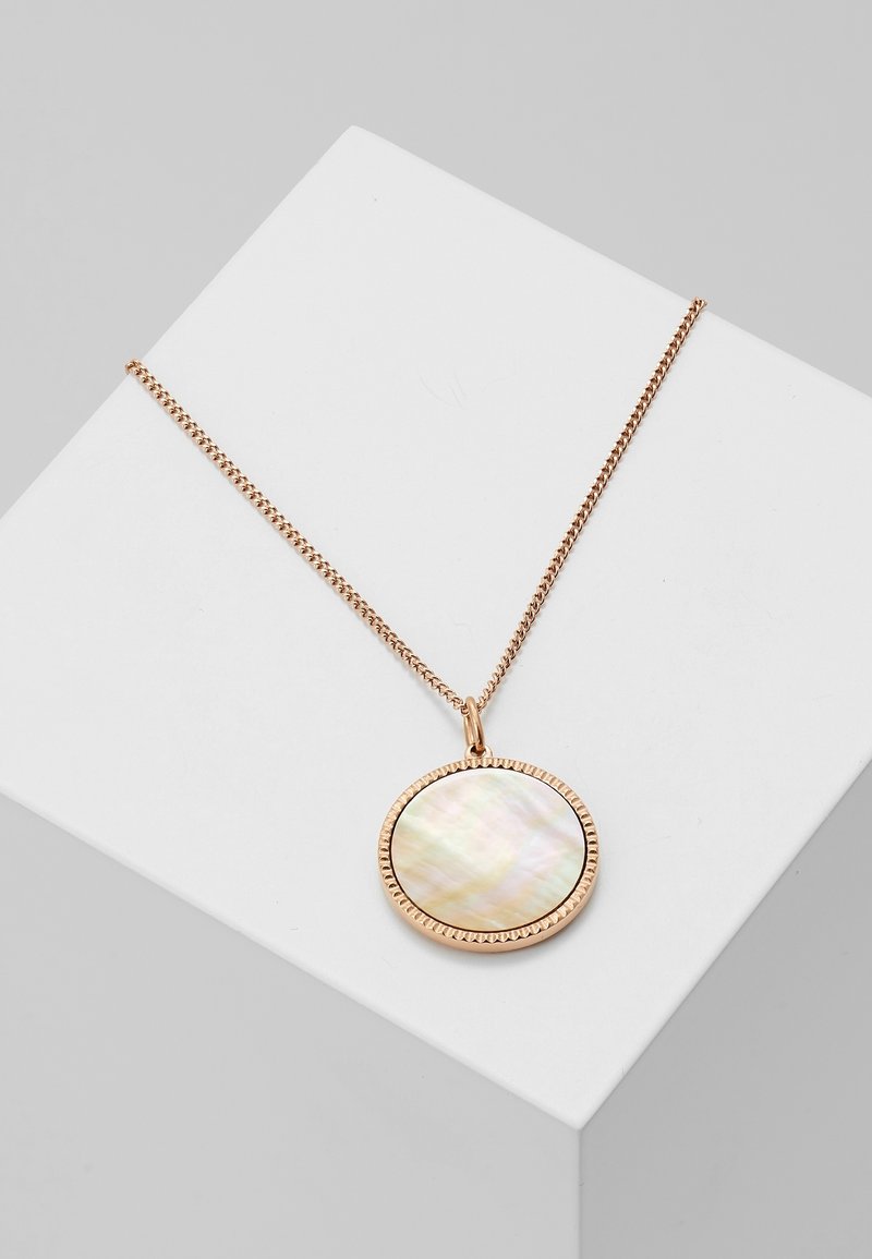 Collier en chaîne dorée avec pendentif rond en nacre orné d’une bordure dorée texturée, présenté sur une surface blanche inclinée.