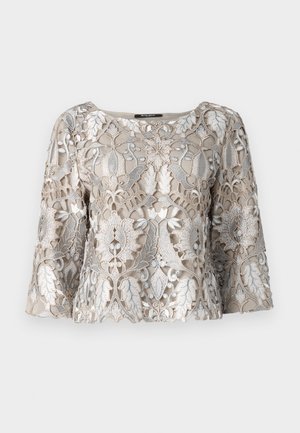 Haut beige brodé avec fils d'argent présentant des motifs floraux et de feuilles. Décolleté arrondi et manches évasées ; finition en tissu texturé.