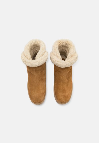 Tan suede ankle boots with a folded, cream faux fur collar. Rounded toe and flat sole; soft texture enhances warmth and comfort.