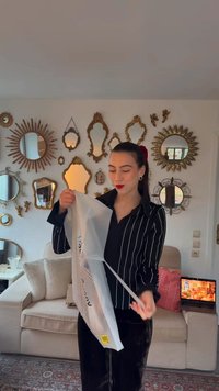 Przezroczysta plastikowa torba trzymana przez osobę, z widoczną etykietą. Osoba ubrana jest w czarną bluzkę w paski i trzyma sznurki torby.