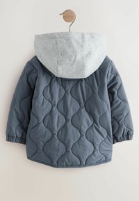 Veste matelassée bleu marine avec capuche en sweatshirt grise. Caractéristiques : manches élastiques, coutures courbées et ourlet arrondi. Texture lisse.