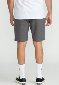 Gray, knee-length shorts in a heathered fabric, with a straight fit. Worn with white socks and black sneakers, view from the back.