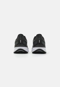 Black athletic shoes with a breathable mesh upper, padded heel, reflective accents, and a white midsole. Curved black outsole design.