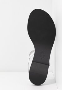 Białe skórzane sandały z gładką czarną podeszwą, z krzyżującymi się paskami i minimalistycznym wzornictwem. Wytłoczone logo na wkładce.