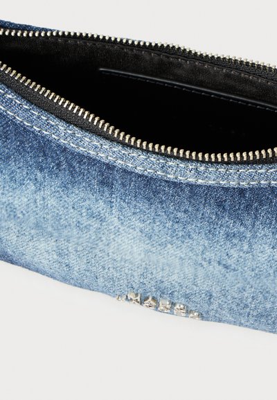 Džínová kabelka do ruky s prechodovou modrou farbou, vybavená strieborným zipsom a čiernou vnútornou podšívkou. Doplnok tvorí výrazný nápis na boku.