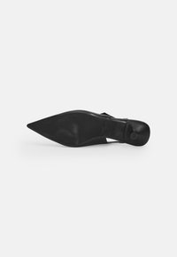 Black stiletto heel shoe with a pointed toe and cut-out design. Smooth leather material with a rubber sole and a small rounded heel.
