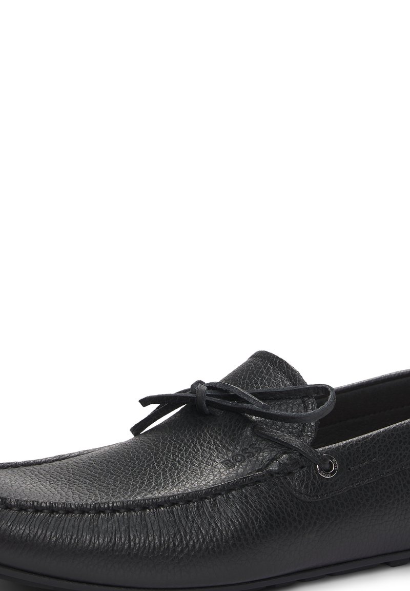 Mocassino in pelle nera con finitura testurizzata, dettagli in pizzo e accentuazione in occhioletto color argento. Design con punta arrotondata e suola piatta.