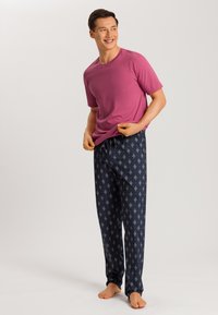 Paarse t-shirt met korte mouwen gecombineerd met marineblauwe pyjamabroek met een geometrisch patroon in lichtroze en crème, gemaakt van zachte stof.