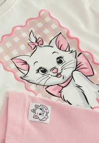Gato de dibujos animados blanco con orejas rosas y lazo sobre un fondo rosa a cuadros impreso en tela blanca sobre tela rosa acanalada con una etiqueta de gato a juego.
