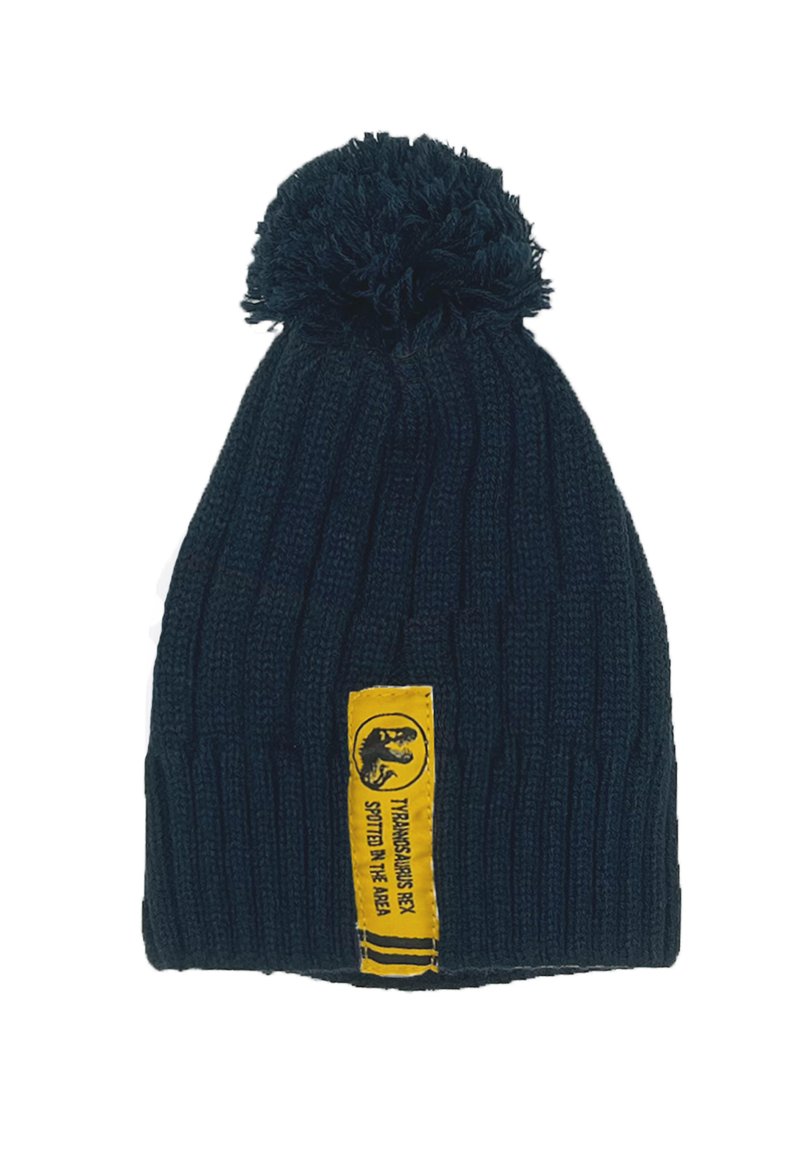 Donkerblauwe gebreide muts met een pompon bovenop en een gele label met een grafisch ontwerp en tekst. De textuur is geribbeld en zacht.
