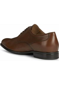 Chaussure habillée en cuir marron avec un bout rond, texture lisse, détails de couture subtils et un petit talon en caoutchouc noir.