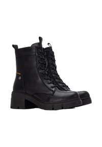 Botas de tobillo de cuero negro con un tacón de goma grueso, cordones en la parte frontal y un detalle lateral que incluye un pequeño elemento metálico.