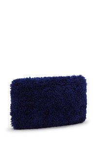 Bolso de mano rectangular de color azul marino con un exterior suave, esponjoso y texturizado, de pie sobre una superficie blanca.