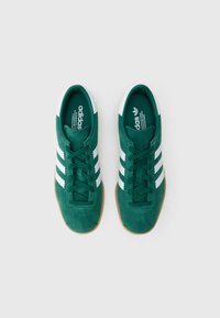 Πράσινα sneakers από σουέντ με λευκό σχεδιασμό τριών ραβδώσεων και λεπτομέρειες. Λαστιχένια σόλα. Περιλαμβάνει το λογότυπο "adidas" στη γλώσσα και στην εσωτερική σόλα.