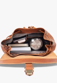 Open brown leather bag containing notebooks, laptop, stainless steel water bottle, phone, and white earbuds case on striped fabric lining.