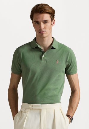 Polo verde dintr-un material texturat, având un guler ribbit și o clapetă cu două butoane, cu un mic logo brodat pe piept.