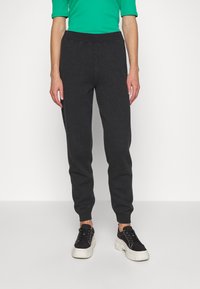 Pantaloni jogger grigio scuro realizzati in tessuto morbido, con vita elasticizzata e polsini a coste. Abbinati a sneakers nere.