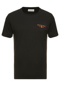 Camiseta negra de algodón de manga corta, con cuello redondo y texto en naranja "ALMAS DEVOTADAS" en la parte delantera. Textura suave, diseño minimalista.