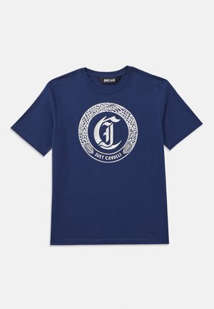 Sötétkék pamut póló, amelyen egy feltűnő fehér kör alakú grafika látható, benne egy stilizált 'C' betű és a "Just Cavalli" felirat.