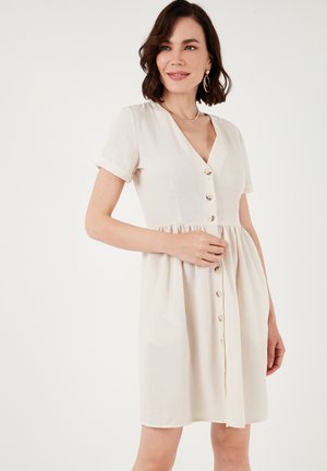 Light beige short-sleeve dress with a V-neck, button-down front, and a flared skirt. Made from a soft, textured fabric.
