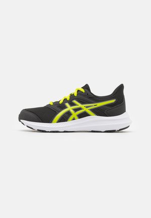 Zapatillas deportivas negras con detalles amarillos, parte superior de malla, media suela blanca acolchada y suela de goma. Presenta un diseño con cordones.