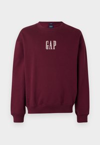 Bordový sveter s okrúhlym výstrihom, manžetami a lemom s rebrovaním. Na prednej strane sa nachádza vyšívané logo "GAP" v bielej farbe. Mäkko textúrovaná látka.