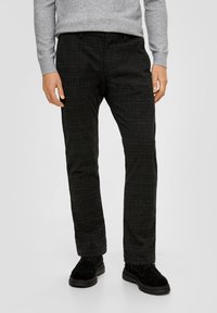 Pantaloni grigi a quadri in un tessuto liscio, con una vestibilità su misura e tasche, abbinati a calzature nere e testurizzate.