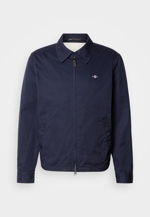 Marineblaue, leichte Herrenjacke mit durchgehendem Frontreißverschluss, Kragen, Seitentaschen und kleinem gesticktem Logo auf der linken Brust.