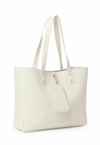 Sac fourre-tout en cuir blanc avec deux anses, fermeture éclair et étiquette amovible avec lettrage en relief. Texture lisse, design minimal.
