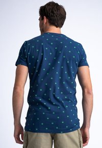 Tricou bleu marin din bumbac, cu un model de mici simboluri solare verzi. Mâneci scurte și guler rotund, material texturat și moale.