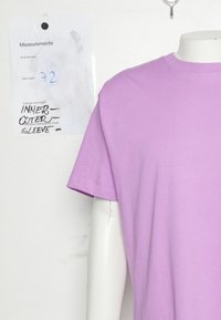 Fialové tričko s krátkým rukávem vystavené na manekýně, s kulatým výstřihem a hladkou texturou. Je viditelná štítek s měřeními.