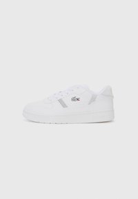 Hvit sneaker med glatt stoffoverside, perforerte detaljer, sølvfargete accenter, klassisk snøringdesign og teksturert gummisåle.