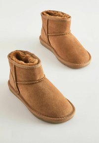 Bruna mockakängor med mjukt foder av päls, rund tå och gummisula. Har sömnadsdetaljer och en enkel slip-on-design.