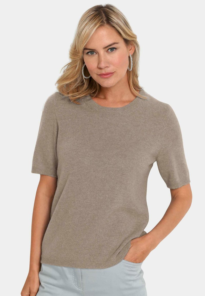 Pull en tricot beige à manches courtes et col rond, avec une texture en côtes et de subtils détails au niveau de l'ourlet latéral.