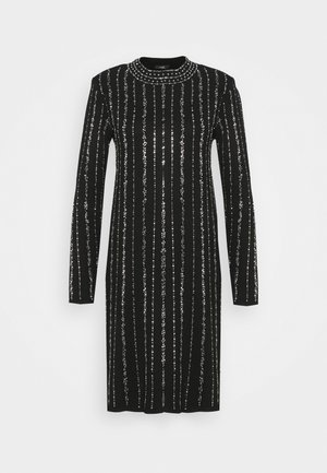 Robe noire à manches longues et longueur genou, avec des rayures verticales en sequins argentés et un col rond décoré de sequins horizontaux.