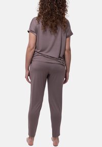 Set da loungewear in due pezzi realizzato in tessuto morbido e leggero. La parte superiore ampia e i pantaloni affusolati sono di un colore marrone tenue.