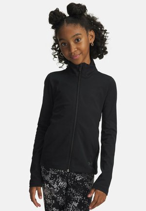 Schwarze Reißverschlussjacke aus glattem Stoff mit langen Ärmeln, hohem Kragen und figurbetontem Schnitt. Kombiniert mit gemusterten, dunklen Leggings.