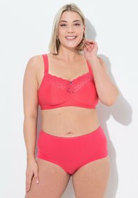 Reggiseno rosa corallo con dettagli in pizzo, texture a pois e spalline regolabili, abbinato a un perizoma a vita alta coordinato. Tessuto liscio, design semplice.