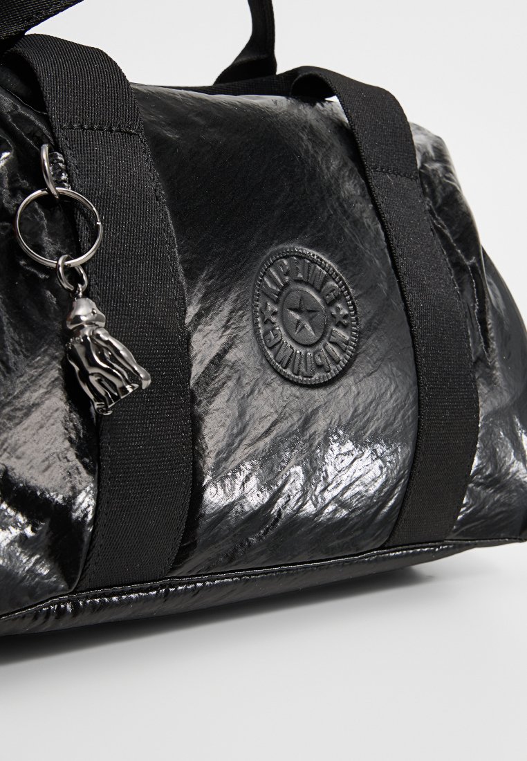 Borsa duffel nera realizzata in materiale lucido, con manici in tessuto nero, un patch rotondo con logo e un accessorio charm in argento.