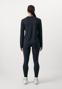 Long-sleeve black athletic top and matching leggings, made of a smooth, stretchy fabric. Includes logo detail on leggings and a clean design.