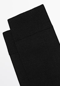 Calzini neri con polsino a coste texturizzato. Il materiale è liscio ed elastico, con un design semplice a tinta unita senza motivi.