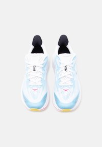 Ζευγάρι από λευκά και ανοιχτό μπλε παπούτσια τρεξίματος με μαύρο εσωτερικό επένδυση,  λευκά κορδόνια και μικρά ροζ και κίτρινα σημεία, φωτογραφημένα από πάνω.