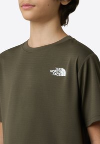 Olive zelena majica iz mehkega tekstila, z rebrastim okroglim izrezom in belim logotipom The North Face na levem prsnem delu.