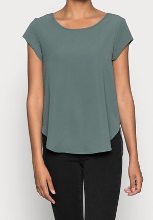 Top de manga corta en verde apagado, confeccionado en una tela suave. Presenta un escote redondo y un dobladillo curvado, combinado con pantalones negros.