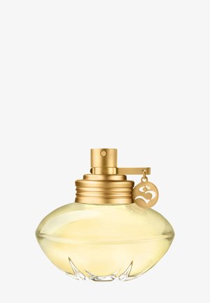 Flacon de parfum rond en verre avec un liquide jaune pâle, un pulvérisateur doré et un charme en or avec un symbole stylisé attaché.
