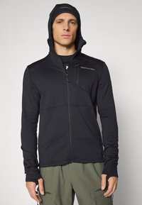 Giacca nera con zip, dalla finitura testurizzata, design aderente e cappuccio. Presenta una tasca sul petto e aperture per i pollici nelle maniche.