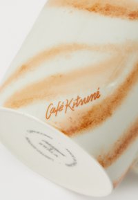 Keramický hrnček s lesklým bielym telom, zdobený oranžovými vírmi a nápisom „Café Kitsuné“ písaným kurzívou. Hladká textúra, zakrivený tvar.