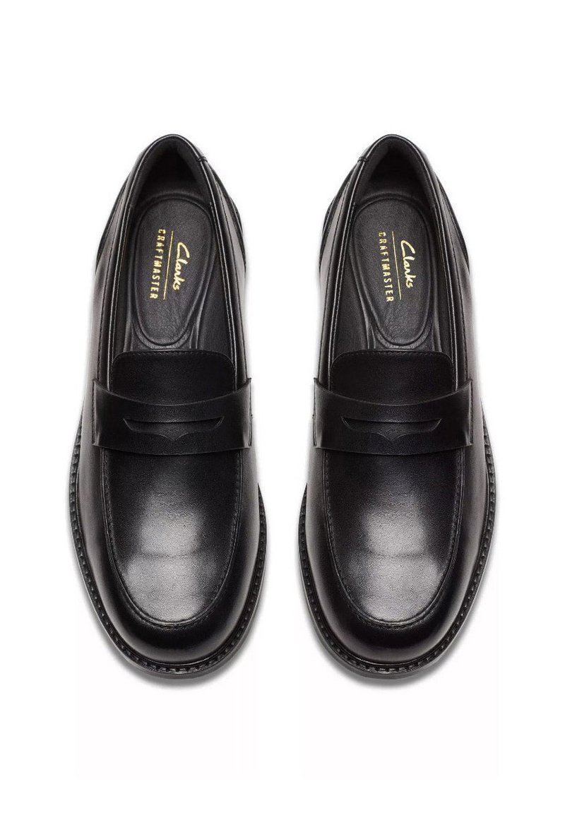 Mocassins en cuir noir avec une texture lisse, bout arrondi et une sangle insérée. Caractéristiques : logo embossé et couture contrastante le long de la semelle.