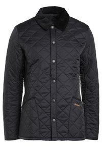 Veste matelassée noire avec un col en velours côtelé, des boutons-pression et une poche latérale avec un logo Barbour orange. Texture lisse et coupe ajustée.